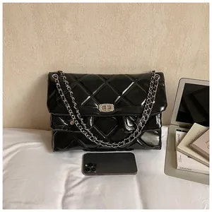 Close-up of black quilted chain bag with glossy finish and crystal-encrusted buckle