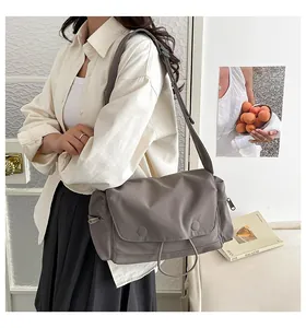 Dettaglio di una grande borsa a tracolla grigio-marrone con spallina larga e coulisse