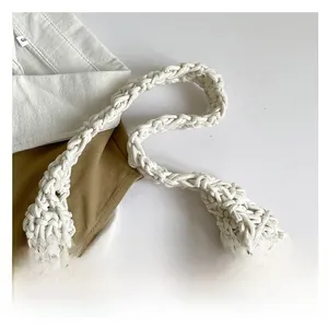 Detail of hand-woven crochet patterns and reinforced handles on this white tote bag