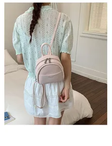 Close-up of light pink mini backpack with adjustable straps and front pocket detail