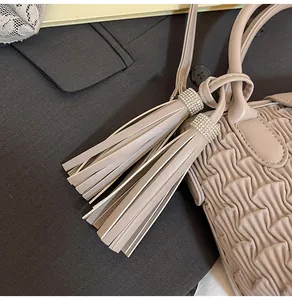 Detailed view of beige pleated bucket bag with crystal embellished leather tassels