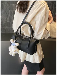Detail of black pebbled Boston bag with silver hardware and plush bunny charm accessory