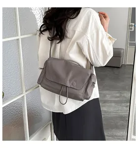 Dettaglio di borsa a tracolla in nylon grigio con tracolla larga e design con patta