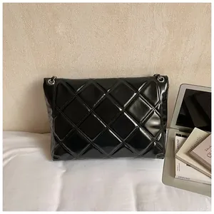 Detail of a black quilted leather shoulder bag with glossy finish and silver metal eyelets