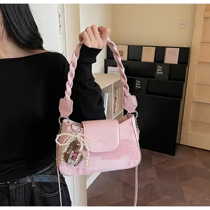 Pink vintage textured square shoulder bag with woven handle and pearl pony charm detail