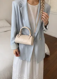 Chic cream white cylinder Boston bag shown styled with a modern minimalist outfit