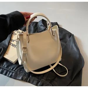 Dettaglio borsa a secchiello crema con pelle PU liscia e supporto manico in metallo