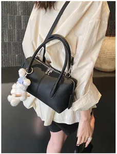 Detail of black pebbled leather Boston bag with double handles and a cute bear charm