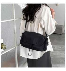 Vista posteriore della modella con borsa a tracolla in nylon nero e cinta regolabile