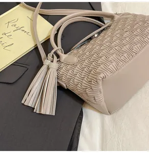 Detail of beige pleated bucket bag with tassel charm on a stylish flat lay setup
