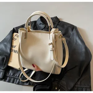 Dettaglio della borsa a secchiello in pelle PU bianca con hardware dorato e tracolla