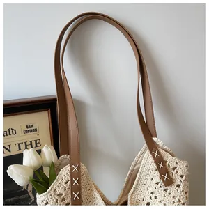 Close-up of crochet hollow knit pattern and leather handles on a beige tote bag
