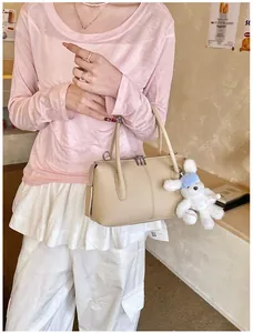 Detailed view of light khaki pillow bag with cute plush bunny charm and silver zipper