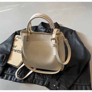 Dettaglio della borsa a secchiello bianco crema con hardware dorato su pelle