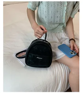 Close-up of black velvet mini backpack with Aimaier embroidery and silver zippers