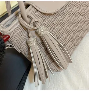 Detail of beige bucket bag featuring water ripple pleats and rhinestone tassel charms