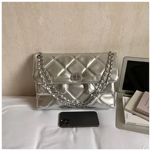 Detail of silver quilted handbag featuring metallic finish and dual chain straps with smartphone