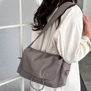 Borsa a tracolla minimalista in tela grigia con tracolla larga indossata da un modello