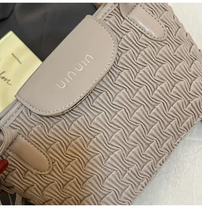 Detailed macro view showing the ripple texture and silver uinun logo on the beige bucket bag