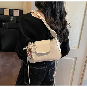 Detail of cream vintage crossbody bag with woven strap and a pearl bear charm