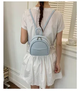Rear view of a model wearing a light blue leather mini backpack with adjustable straps