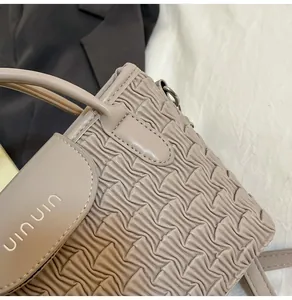 Detailed macro view of the water ripple pleated texture on the beige bucket bag surface