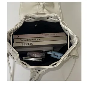 Interior view of white drawstring backpack showing large capacity with books and makeup