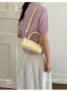 Pale yellow cylindrical crossbody bag shown on model for size and style reference