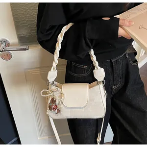 Detail of cream vintage square bag featuring a braided rope handle and hanging charms