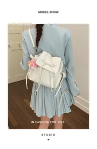 Detail of white PU backpack featuring bow drawstring, side pockets and pink bear charm