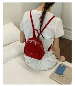 Mini red suede backpack for women shown on a model in a bright minimalist setting