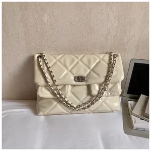 Macro detail of beige quilted crossbody bag with silver twist lock and chain strap