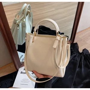 Dettaglio della borsa a secchiello bianco crema con finiture dorate e pelle opaca