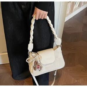 Detail of cream white leather handbag with braided handle and pearl horse charm
