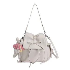 Detail of cream backpack featuring bow drawstring and plush animal pendant on the side