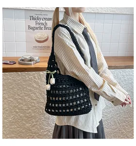 Close-up of black hollowed crochet tote bag with a white flower and green bow charm