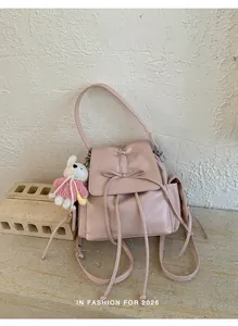 Close-up of pink backpack with bow detail and rabbit plush charm on a textured background