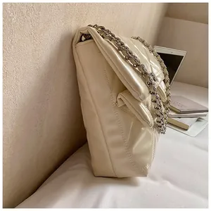 Macro side view of cream quilted chain bag featuring glossy diamond stitching and silver metal