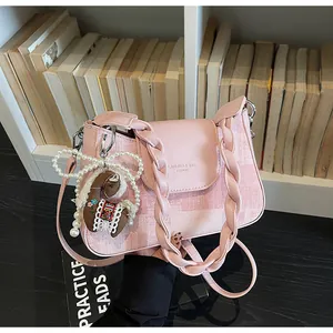 Detail of pink plaid satchel with braided handle and cute horse charm on a bookshelf