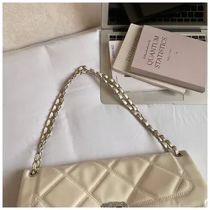 Detail view of cream quilted shoulder bag with silver chain strap on a white background