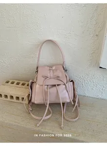 Detail of pink PU leather backpack featuring drawstring bow and magnetic flap closure