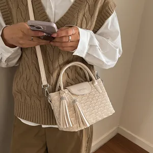 Beige bucket bag with ripple pleats and tassels worn by a model in a minimal outfit