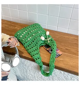 Close-up of green hand-woven knit tote bag with mesh texture and white tulip charm