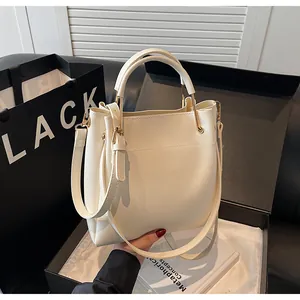 Dettaglio di una borsa a secchiello bianco crema con anelli dorati e tracolla regolabile