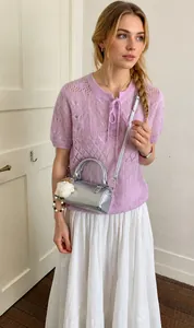 Silver metallic cylinder bag with plush bear charm worn with a purple knit top