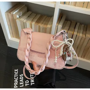 Detail of pink tweed crossbody bag featuring braided handle and pearl horse charm
