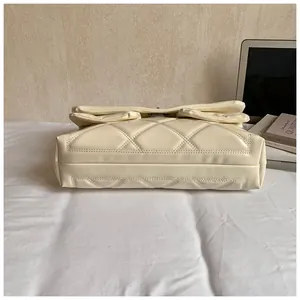 Detailed side view of the quilted cream crossbody bag showing thick base and fine stitching