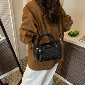 Black water ripple bucket bag with tassel and brand lettering for shoulder or crossbody use