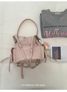 Detailed close-up of pink leather school backpack with side drawstring pocket and doll charm