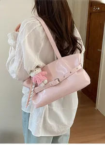 Detail of pink patent leather tote bag with metal buckle and cute plush bear charm